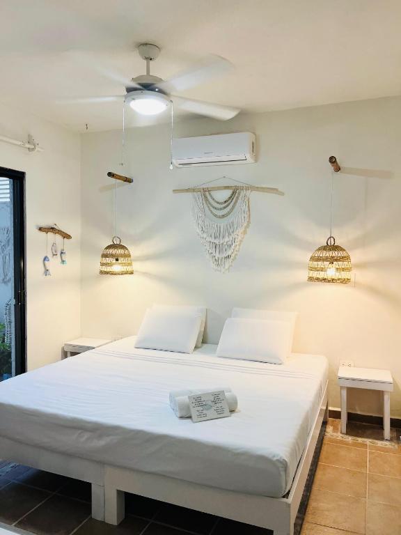 a bedroom with a white bed and a fan at Hotel Boutique Pachamama in Mahahual