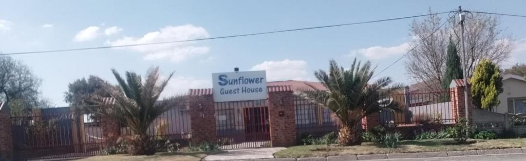 a sign for a building with palm trees in front of it at Sunflower Guesthouse in Ventersburg