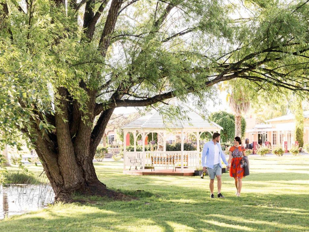 a man and a woman walking in front of a gazebo at Parklands Resort Mudgee in Mudgee