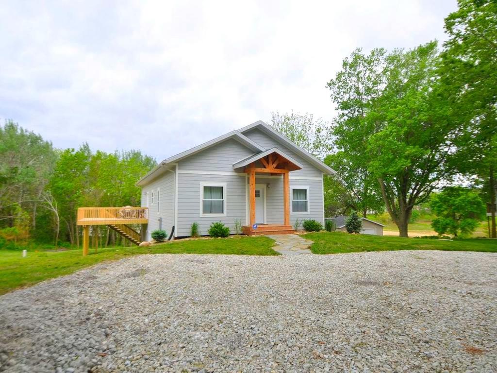 a small white house with a gravel driveway at Comfortable and Modern Cabin Rental on Lake Red Rock near Pella, Iowa in Pella