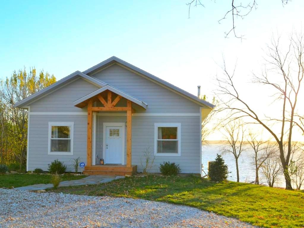 a small white house with a porch and a door at Comfortable and Modern Cabin Rental on Lake Red Rock near Pella, Iowa in Pella