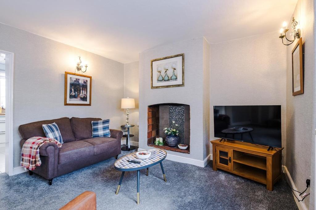 a living room with a couch and a fireplace at Hough Green Cottage in Ashley