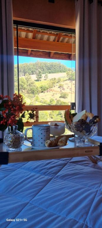 a table with bowls of food on a bed with a window at Chalé Davivi in Socorro