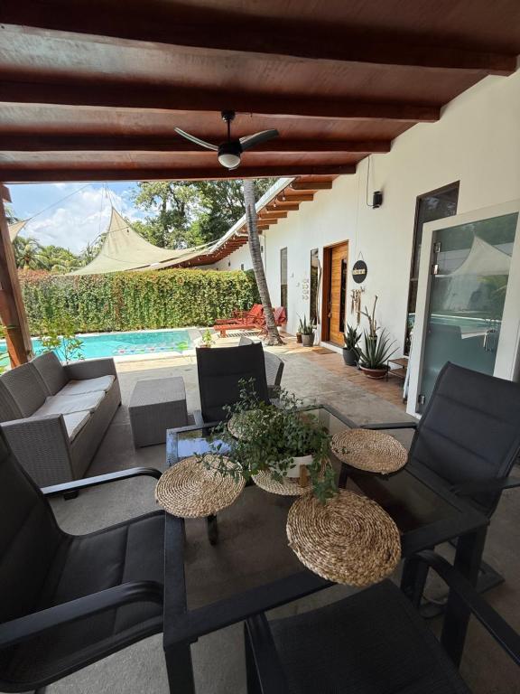 eine Terrasse mit Tisch und Stühlen und einem Pool in der Unterkunft 2 Boho Villa El Sunzal Private Pool BBQ Paradise in El Sunzal