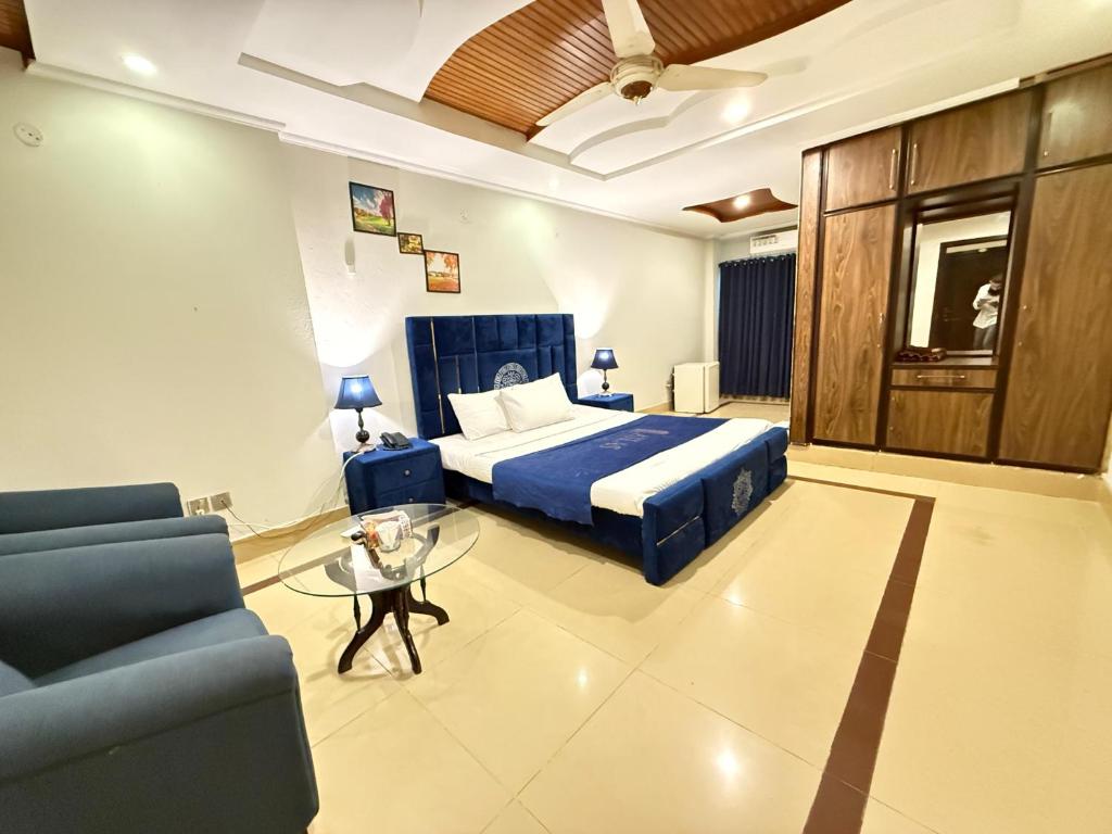 a bedroom with a bed and a couch and a table at Atlas Gold Hotel in Islamabad
