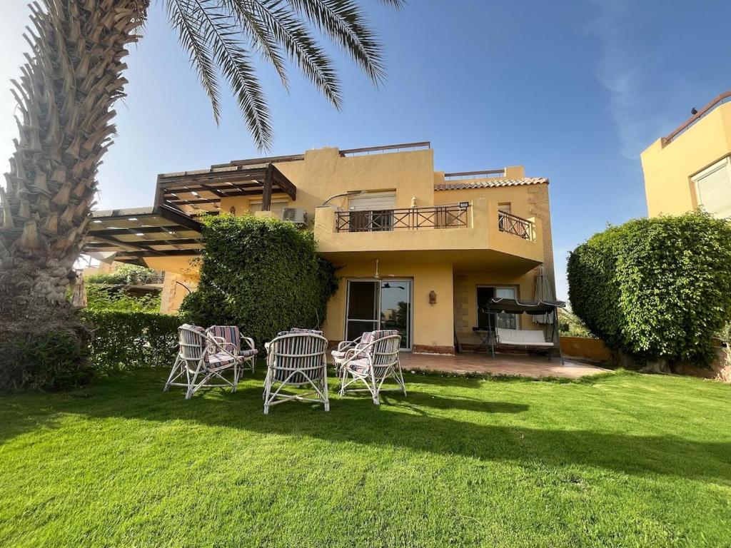 a yard with chairs and a house with a palm tree at Charming beachside 5BDR Villa in Einbay in Ain Sokhna