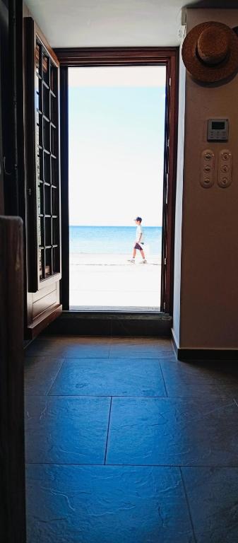 a woman walking on the beach through an open door at Armiriki Seafront House in Afissos