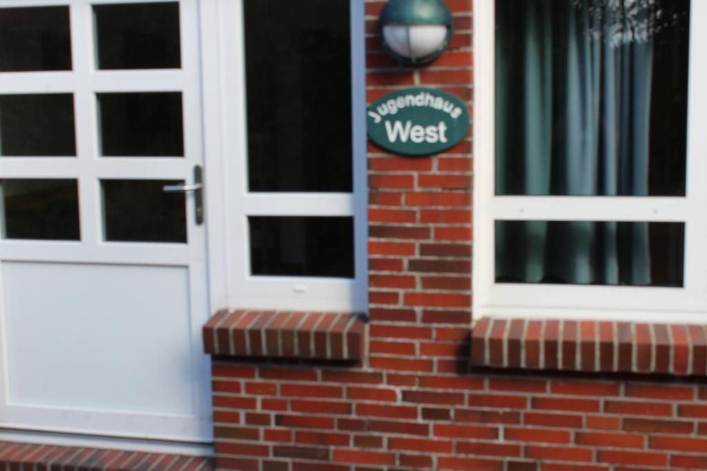 a front door of a brick house with a west sign at Jugendhaus West in Spiekeroog