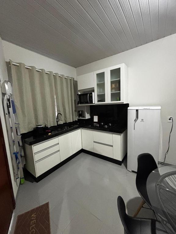 a small kitchen with white cabinets and a refrigerator at Microcasa 02 in Tangara da Serra