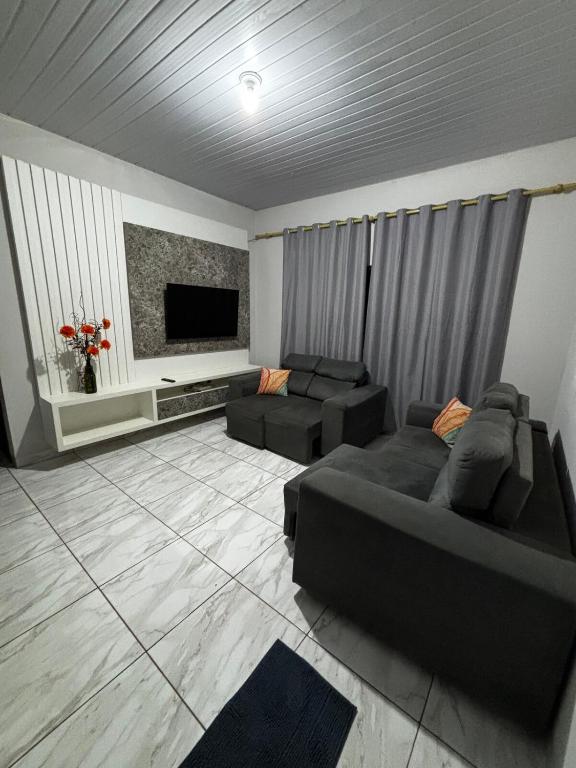 un salon avec deux canapés et une télévision à écran plat dans l'établissement Casa ampla e confortavel, à Tangará da Serra