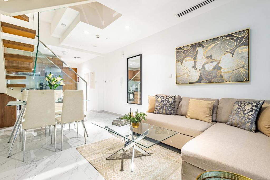 Una sala de estar con un sofá y una mesa de cristal. en Private Rooftop Jacuzzi - Duplex - Masdar City, en Abu Dabi