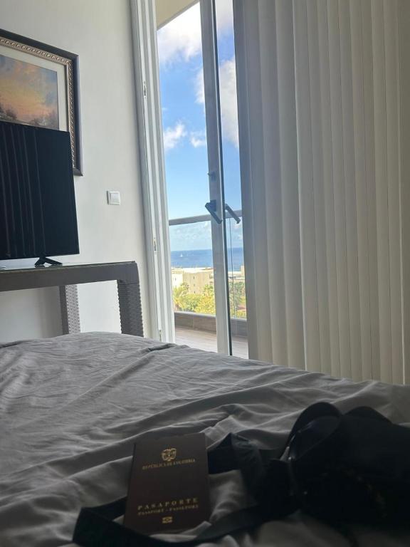 - un livre sur un lit dans une chambre avec fenêtre dans l'établissement Apartahotel curacao, à Willemstad