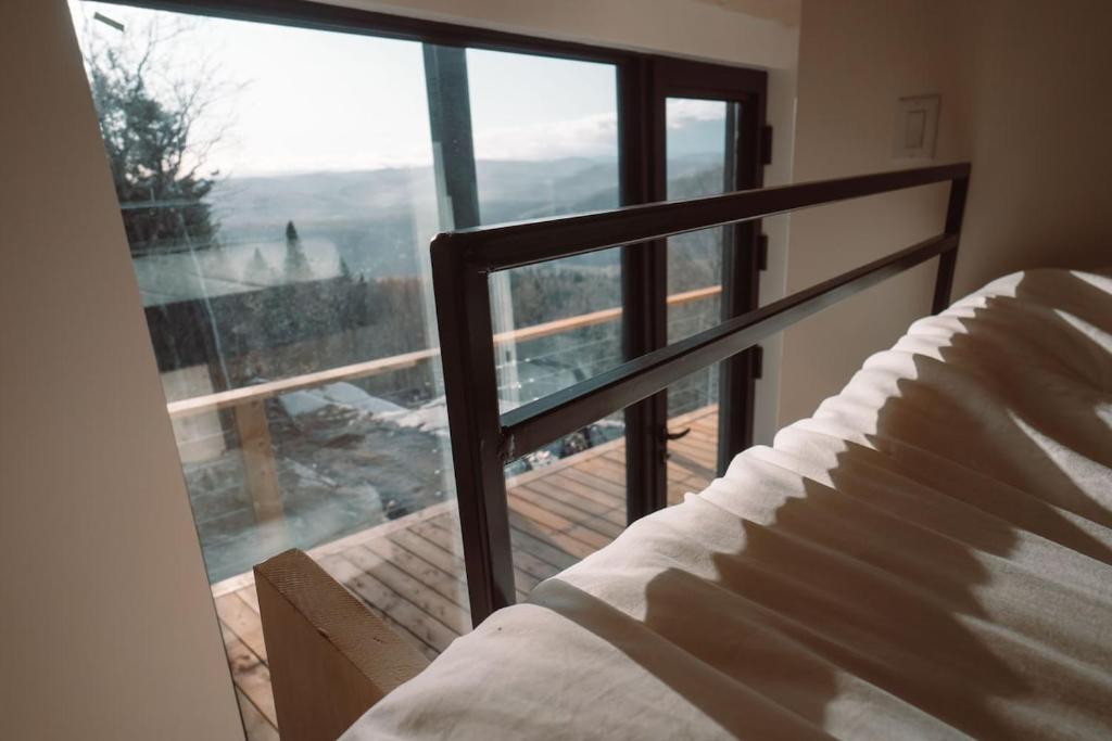 Un dormitorio con una cama y una ventana grande. en Tricera - Panoramic View near Quebec City, en Lac-Beauport
