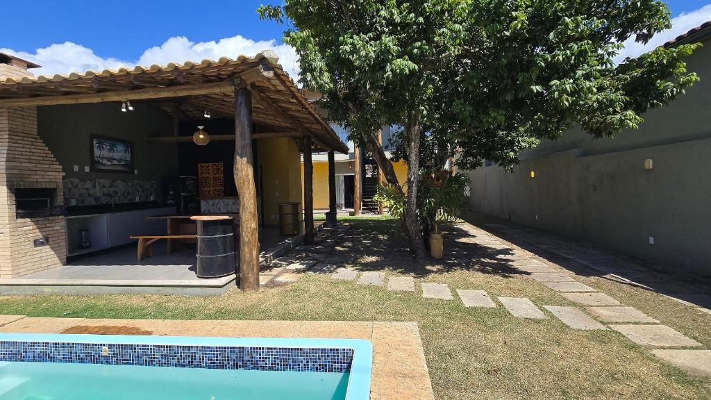 a backyard with a pool and a table and a tree at Casa Temporada Brisa do Mar in Guriri
