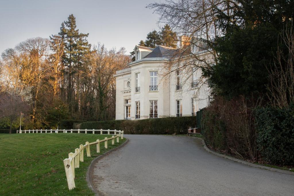 una casa bianca con una recinzione di fronte a un vialetto di Hôtel Demeures de Campagne Domaine de Maffliers - Paris Val-d'Oise a Maffliers