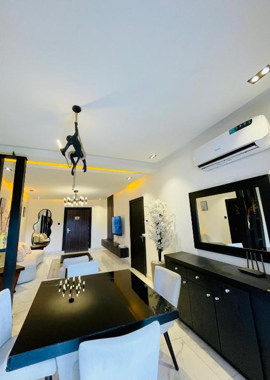 a dining room with a black table and white chairs at Alphavista Luxury Apartments in Port Harcourt