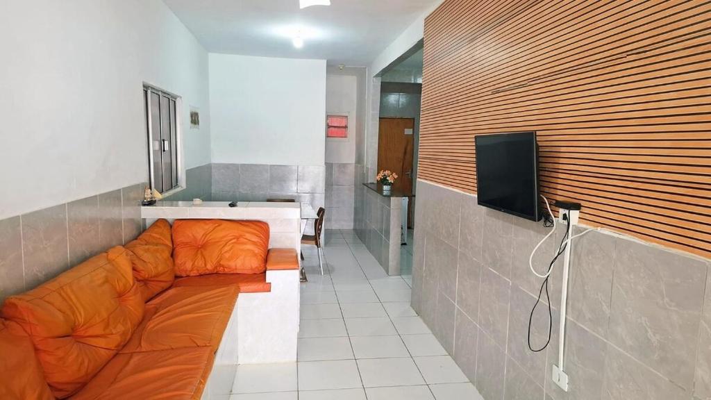 an orange couch in a room with a tv at Enseadabechouse in Cabo de Santo Agostinho