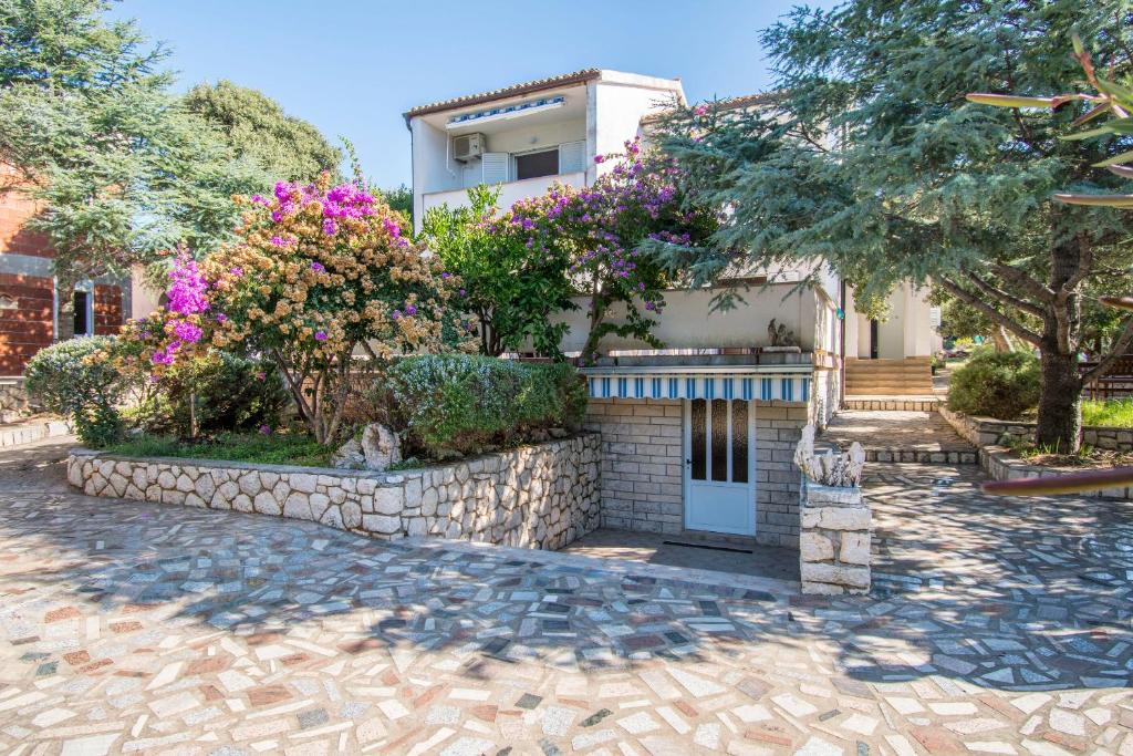 a house with flowers and a stone wall at Apartment Family Ribicic in Mandre