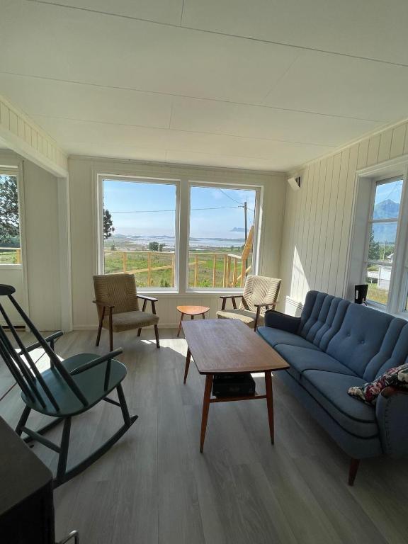 a living room with a blue couch and a table and chairs at Skokkelvika gård in Vestvågøya