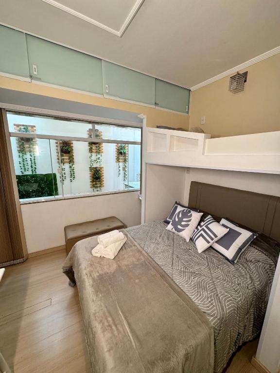 a bedroom with a bed and a large window at Estúdio no Centro Reformado e Decorado in Nova Friburgo