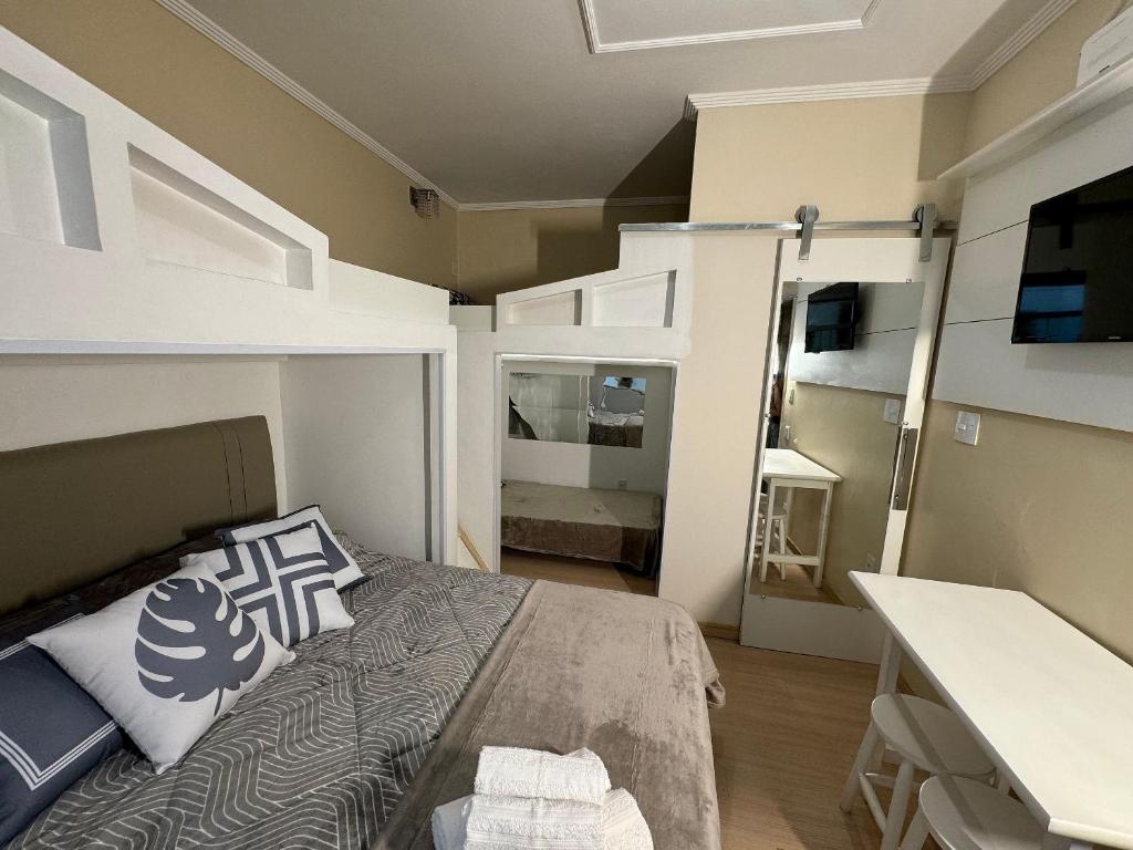 ein Schlafzimmer mit einem Bett und einem Schreibtisch in einem Zimmer in der Unterkunft Estúdio no Centro Reformado e Decorado in Nova Friburgo