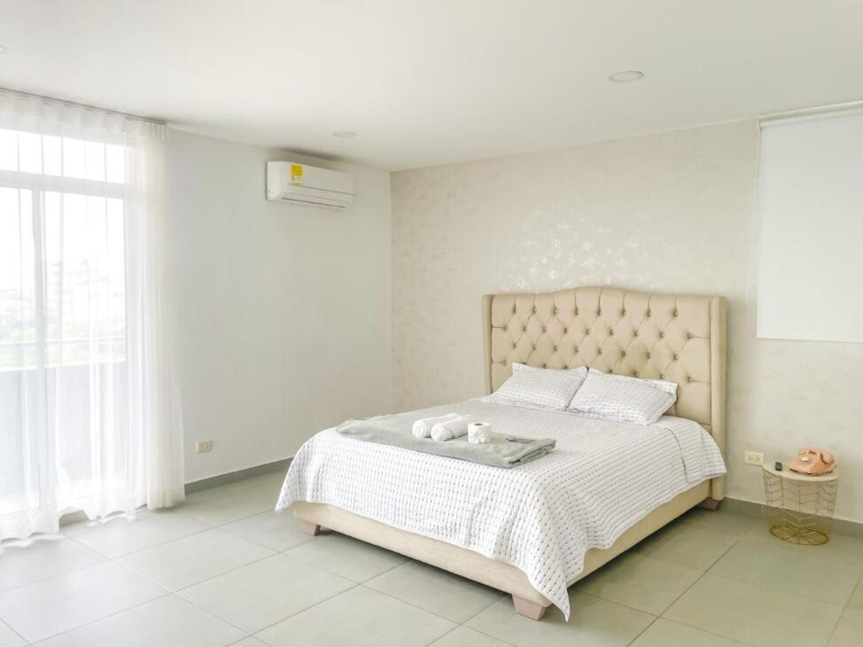 - une chambre blanche avec un grand lit et des draps blancs dans l'établissement Espacioso Apto Moderno! Excelente Ubicación Norte de Barranquilla, à Barranquilla