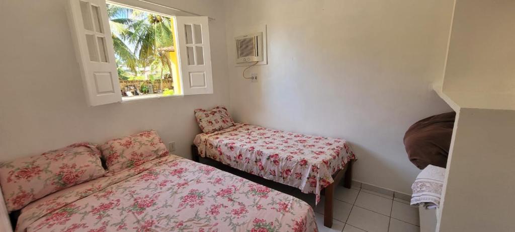 a room with a bed and a chair and a window at Pousada Veruschka Santiago in Maragogi