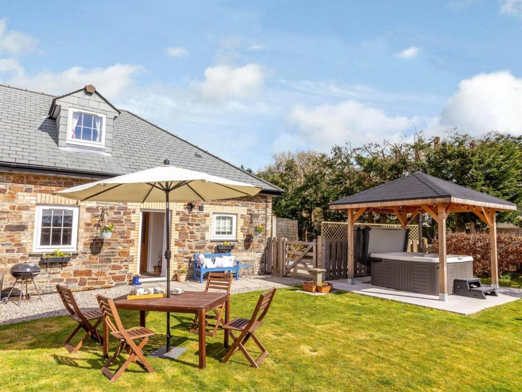 a garden with a table and an umbrella and a grill at 2 Bed in Launceston 41992 in Saint Giles on the Heath