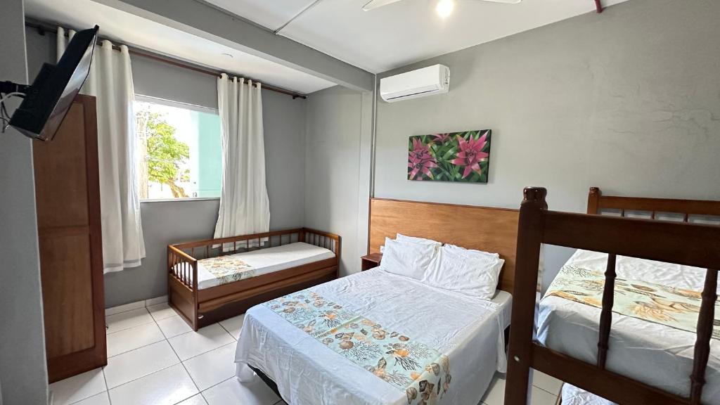 a bedroom with two beds and a window at Pousada Suíte Verde Mar in Ubatuba