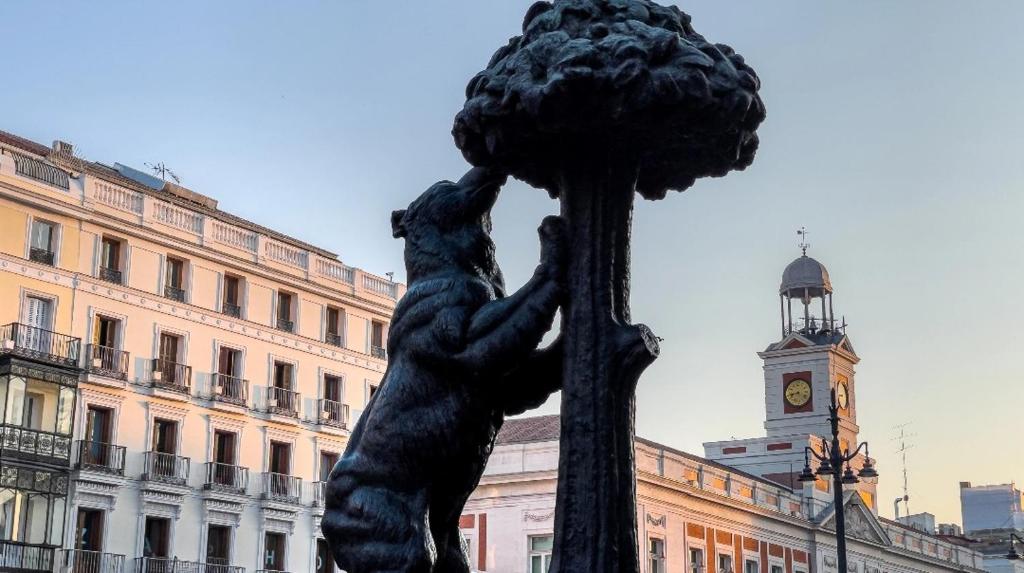 una estatua frente a un edificio con una torre de reloj en Happy Travel, en Madrid