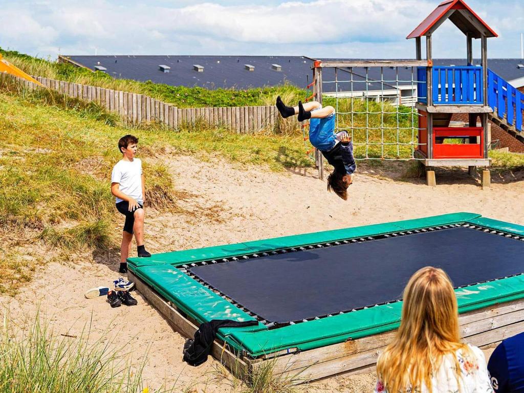 two people playing on a trampoline on the beach at 2 person holiday home in Ringkøbing in Ringkøbing