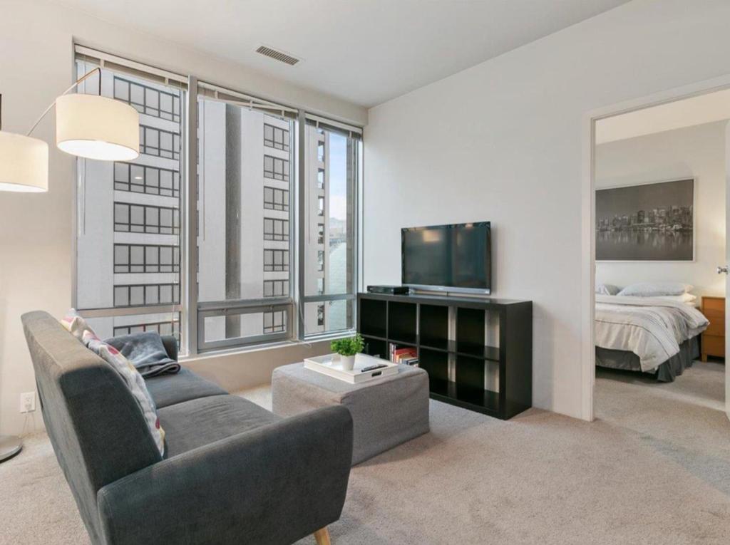 a living room with a couch and a tv and a bed at Cozy Condo in the heart of the city in Vancouver