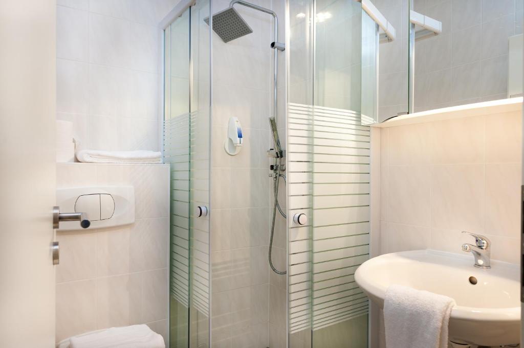 a bathroom with a glass shower and a sink at Hotel Castellana in Lessien