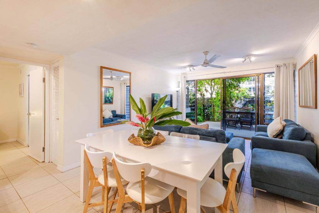Una sala de estar con una mesa y sillas blancas. en Sandy Toes, en Port Douglas