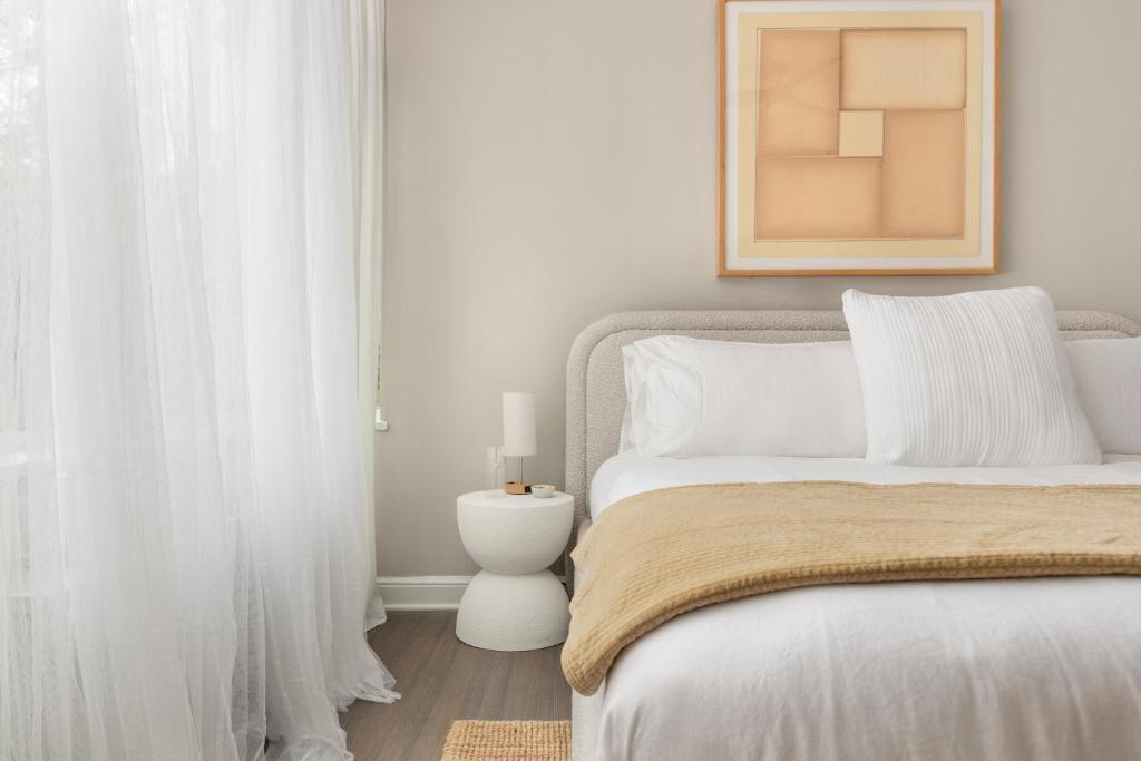 een witte slaapkamer met een bed met witte gordijnen bij Refined 2BR King Suite with Gym and Lounge - The MORGAN in Arlington