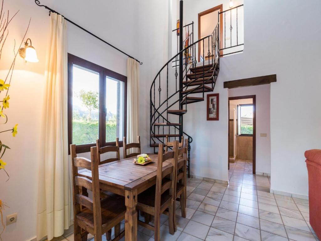 a dining room with a wooden table and a spiral staircase at Cozy Countryside Retreat in Pozo Alcón in Cuenca