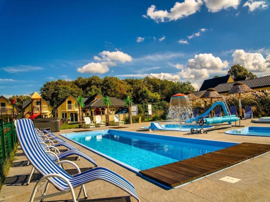 a swimming pool with two chairs and a playground at Comfortable holiday homes, pool and whirlpool in Ustronie Morskie