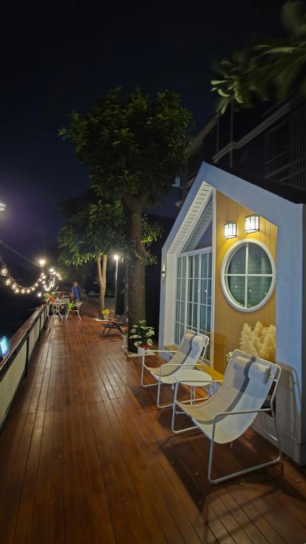 a deck with chairs and a tree and a building at Grace Riverfront in Lat Krabang