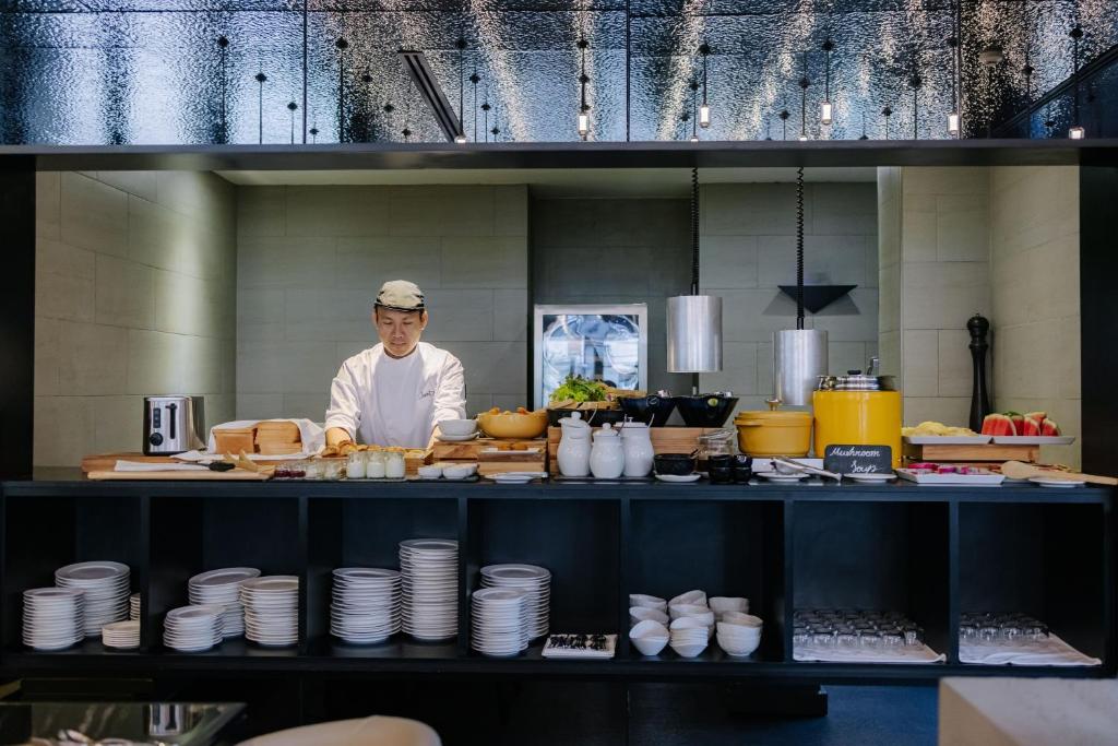 A chef prepares food at the centre of an open breakfast buffet.