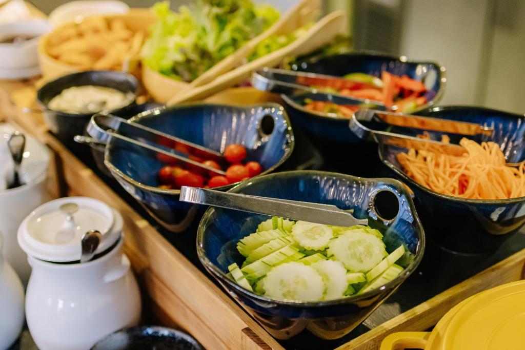 A buffet salad and vegetable station with cucumber, tomatoes, carrots and leafy greens.