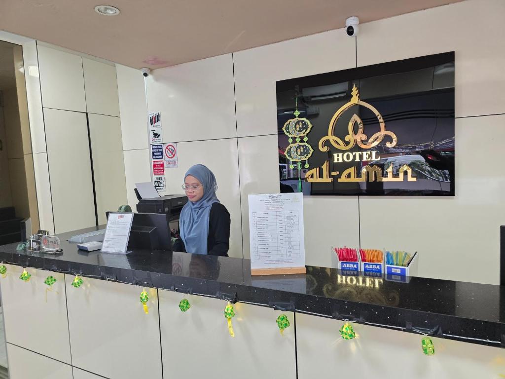 a woman sits at a counter in a hotel room at Budget Hotel AL Amin in Kuala Lumpur