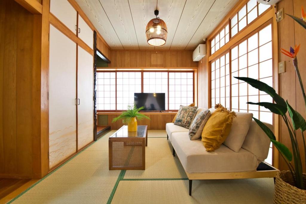 ein Wohnzimmer mit Sofa und Fernseher in der Unterkunft 北谷町宮城戸建て in Hamakawa