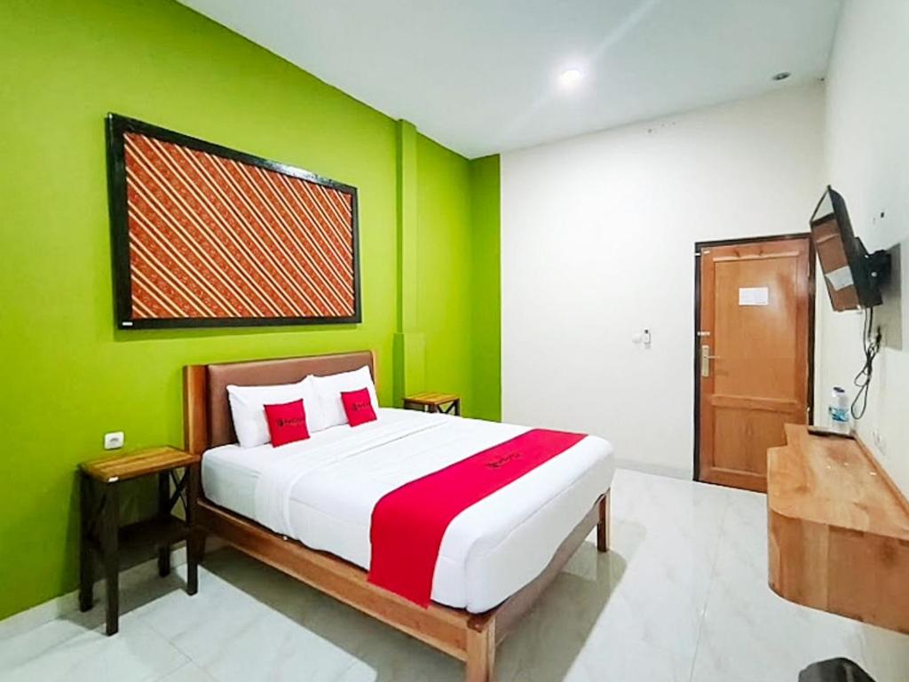Un dormitorio con una cama con una pared verde. en RedDoorz at Flory Hotel Jalan Parangtritis, en Timuran