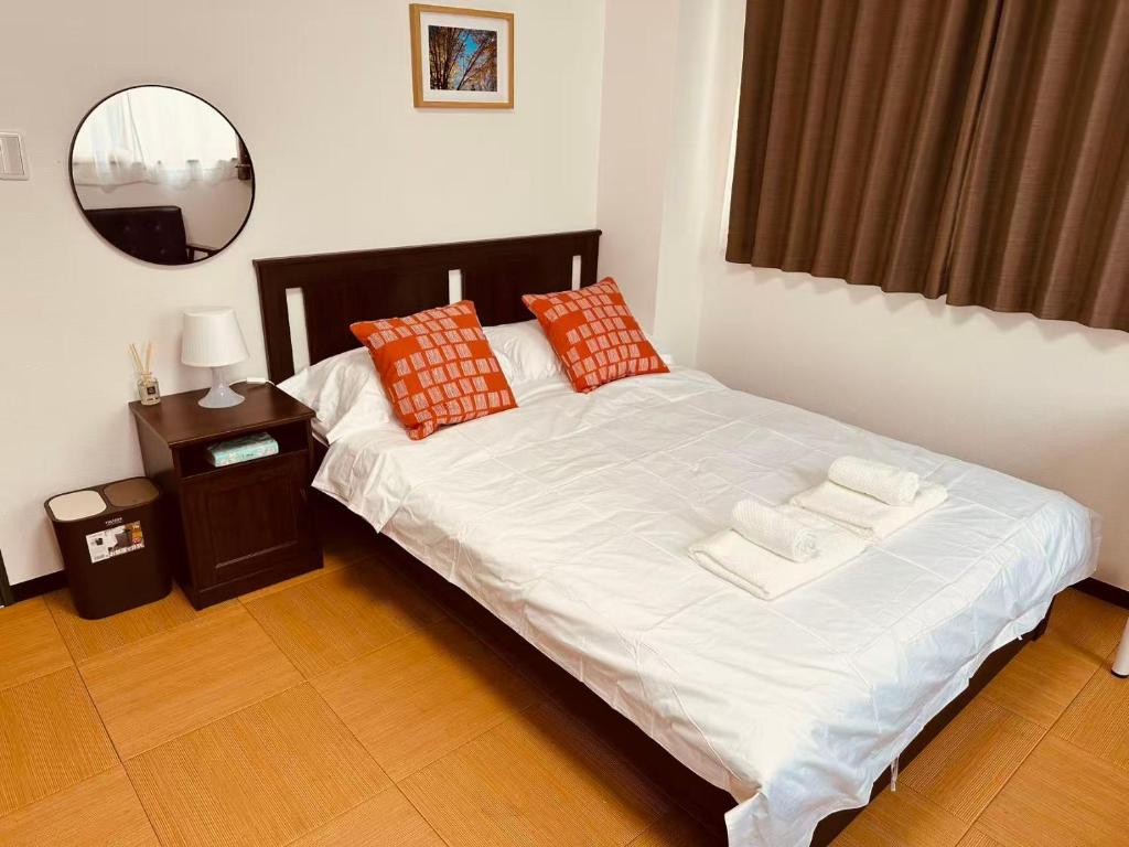 a bedroom with a white bed with pillows and a mirror at Rest Collection SEIWA LODGE Tokyo in Tokyo