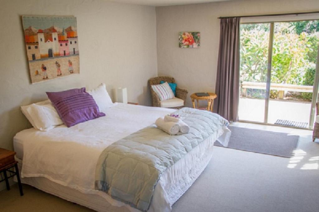 a bedroom with a large bed with a stuffed animal on it at Taigh na Mara Bed and Breakfast in Whitianga