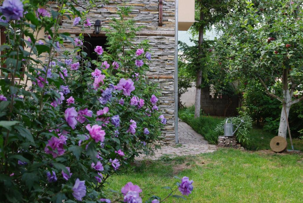 a garden with pink flowers and a stone building at Guesthouse Viktoria in Peshtera