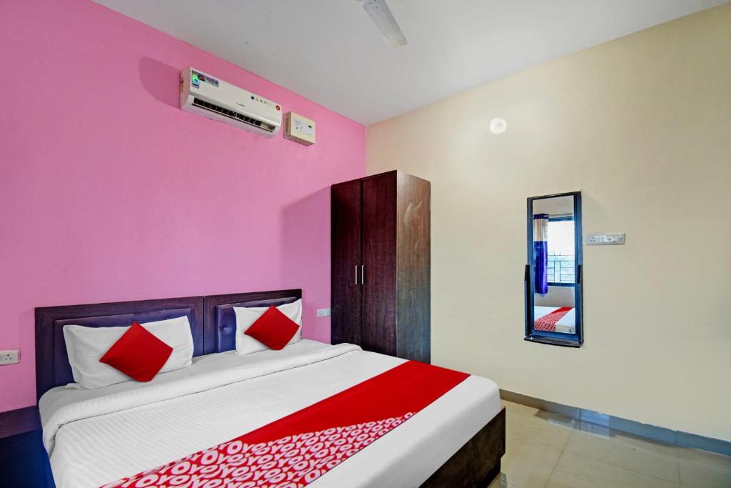 a bedroom with pink walls and a bed with red pillows at Hotel O SR PALACE in Bārang