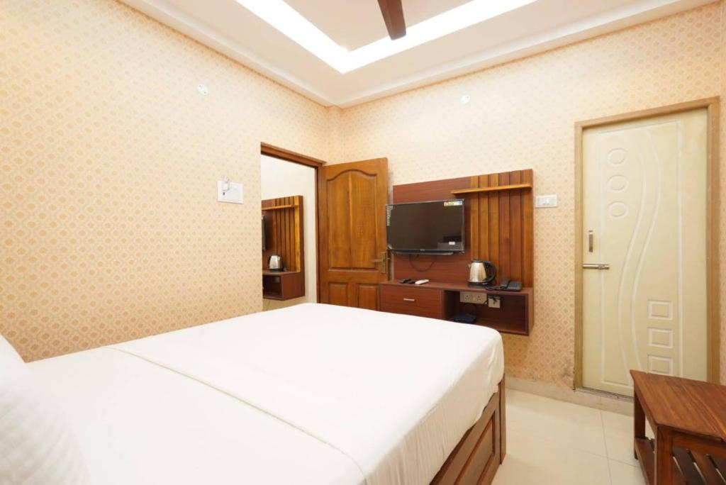 Un dormitorio con una cama blanca y un televisor. en Easwarresidency, en Chennai