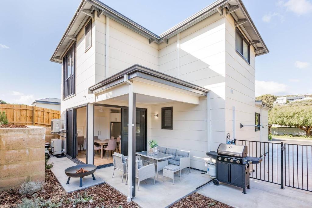 a white house with a patio with a grill at Yallingup Lagoon Beach House in Yallingup