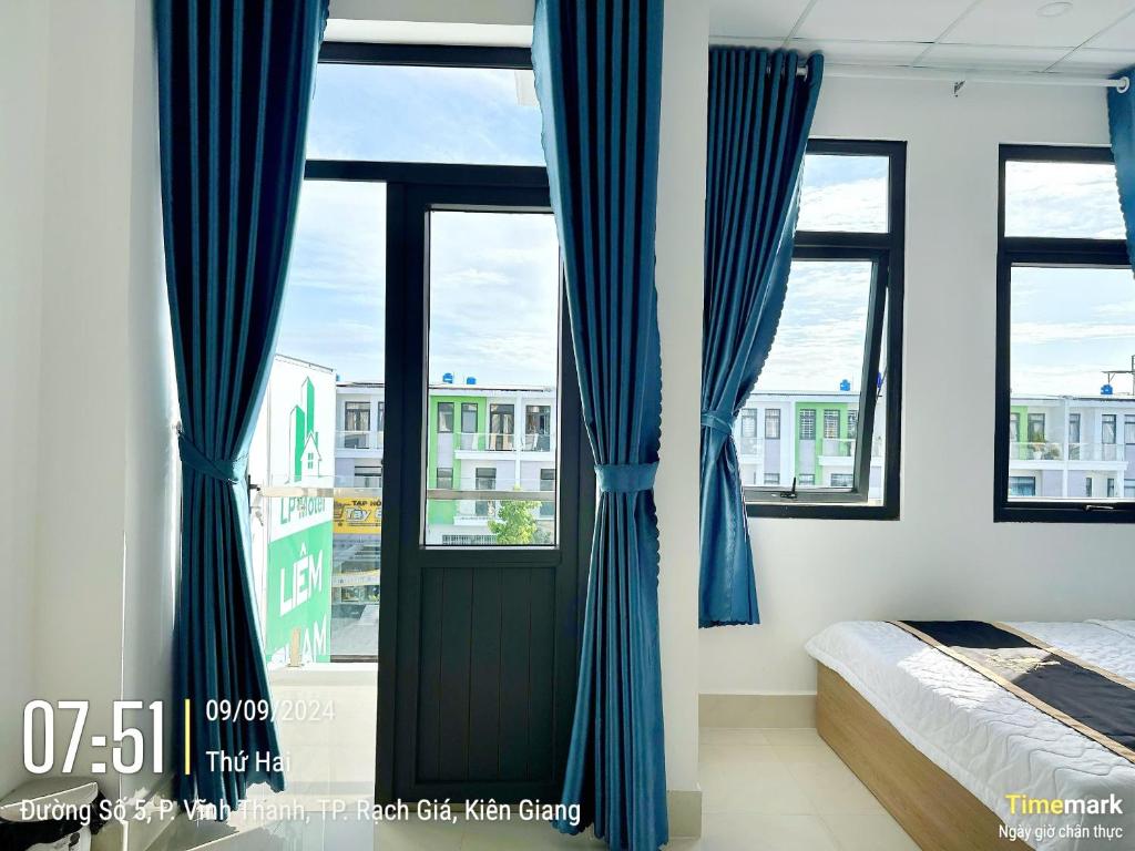 Schlafzimmer mit blauen Vorhängen, einem Bett und einem Fenster in der Unterkunft LIÊM PHẠM MOTEL - Cách cảng 400m in Rạch Giá